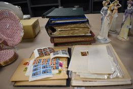An album containing 1990s film related postcards, an album of Queen Elizabeth II stamps, plus