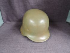 A German WWII Steel Helmet having leather liner and chin strap, possible sand/yellow/buff colour