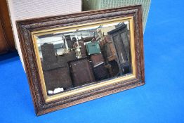 A carved oak and bevelled glass mirror, of rectangular form with gilt slip 57cm x 78cm