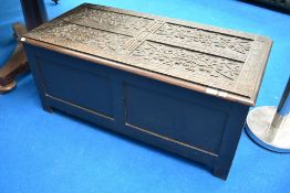 A traditional oak blanket box having heavy carved top and plain panels to front and sides, width