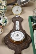 An antique carved oak Aneroid barometer having Arts and Crafts styling, sold alongside a brass cased