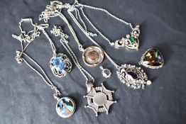 A selection of silver and white metal pendants, several stamped silver including butterfly wing,