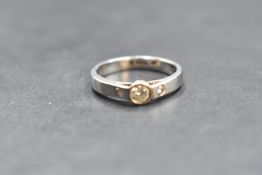 An artisan style diamond trilogy ring having a central diamond in collared mount flanked by two