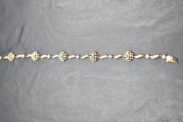 A 9ct gold bracelet having five floral style emerald and diamond chip panels interspersed by six