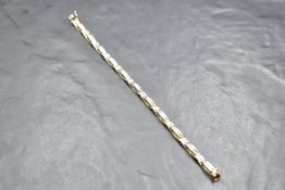 A 9ct white and yellow gold articulated bracelet having eleven panels each containing twelve small