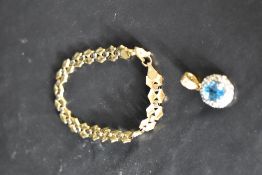 A yellow metal pendant stamped 750 having a central blue topaz with cubic zirconia surround, and a