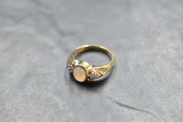 An opal dress ring having a trio of diamond chips to each shoulder on a 9ct gold moulded loop,