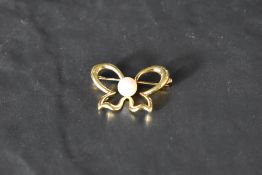A yellow metal brooch stamped 750 modelled as an open bow having a central cultured pearl, approx