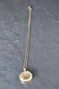 A 9ct gold locket of circular form having engraved decoration to front, on a rose gold chain bearing