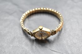 A ladies 9ct gold wrist watch by Excalibur having Arabic numeral dial to champagne face in gold case