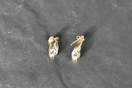 A pair of yellow metal stud earrings having moulded drops with blue topaz and diamond chips, no