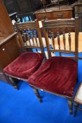 A pair of Victorian oak dining chairs having spindle backs and over stuffed seats