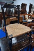 A Victorian ebonised chair having spindle back and rush seat with turned legs and supports