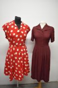 Two 1940s day dresses, comprising; burgundy with white dots, and red seersucker dress with large