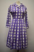 A late 1950s/ early 1960s cotton day dress having bold purple checked pattern, side metal zip, 3/4