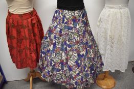 Three 1950s skirts, to include; red cotton with floral pattern and pleats, sheer white lace skirt