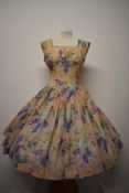 A beautiful 1950s semi sheer seersucker day dress with bright floral pattern, pointed bodice and
