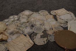 A collection of hand worked d'oyleys and mats in a case, various styles and techniques used.