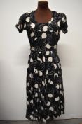 A 140s day dress, having bold print, gathered faux wrap around detail to bust, pleated skirt and
