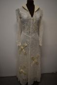 A 1930s lace wedding dress, having cream satin quilted collar, and quilted appliqué crosses to