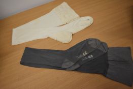 A pair of 1920s white stockings and a pair of 1940s CC42 utility stamped seamed stockings in grey.