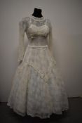 A 1950s tulle and lace wedding dress, having tulle layer over taffeta under dress, full skirt,
