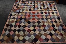 A Victorian patchwork quilt, made up of colourful squares,backed in various white cottons and