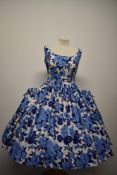 An amazing 1950s cotton day dress, having bold blue rose pattern, scooped neckline and the fullest