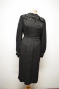 A 1930s black day dress, having unusual collar, side metal zip and belt, re enforcement needed to