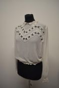 A white crepe georgette and lace 'Eros model' blouse, having long sleeves and button back