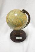 A small vintage tin globe, of traditional arrangement, on a grained tin circular base