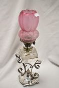 An early 20th Century oil lamp, the moulded glass shade, above a cut glass square reservoir, and