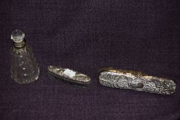 A silver backed clothes brush, a cut glass lidded perfume bottle with silver collar, and a white