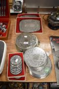 A selection of plated table mats and coasters, some monogrammed with 'A'.