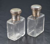 A pair of French white metal topped glass cologne or eau de toilette bottles, the screw-off covers