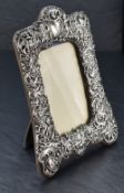 A late Victorian silver-mounted photograph frame, of shaped rectangular form embossed and pierced