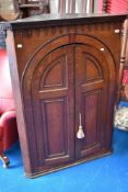 A 19th Century oak corner cupoard, having gothic style panelled doors and dentil cornice, with