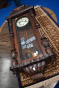 A Victorian Vienna style wall mounted clock with an enamel face and carved mahogany frame.