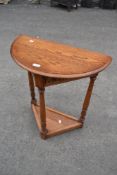 A traditional oak hall table having demi lune top on triform base