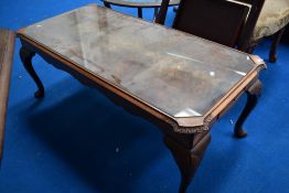 A reproduction walnut and glass topped coffee table