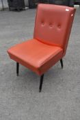 A vintage nursing chair in red vinyl on dansette style legs