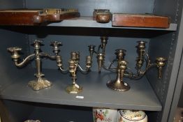 Three silver plated candlesticks, the largest measuring 25cm tall and 46cm across.