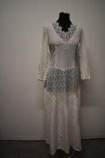 A 1940s white gown having sheer lace panels, long sleeves and side metal zip.