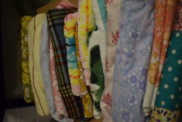 A box full of vintage and retro bedding, towels, a table cloth, a travel rug and similar.