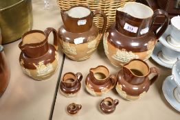 Eight 19th/20th Century Doulton Lambeth stoneware jugs, of graduating sizes, all decorated in relief