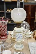 A Victorian opaque glass oil lamp, the body hand painted with stylised blue flowers and heightened