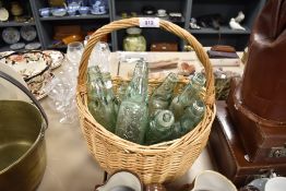 A vintage wicker basket containing various glass Codd bottles, including Neal & Co. Morecambe,