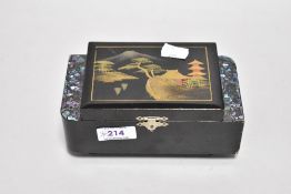A mid century lacquered musical jewellery box, having inlaid paua shell detail and Japanese scene to