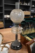 An early 20th century oil lamp, having etched glass shade, clear reservoir and copper column mounted