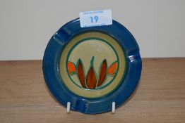 A 1930s Clarice Cliff Fantasque design ashtray, blue glazed border, and having a diameter of 12cm